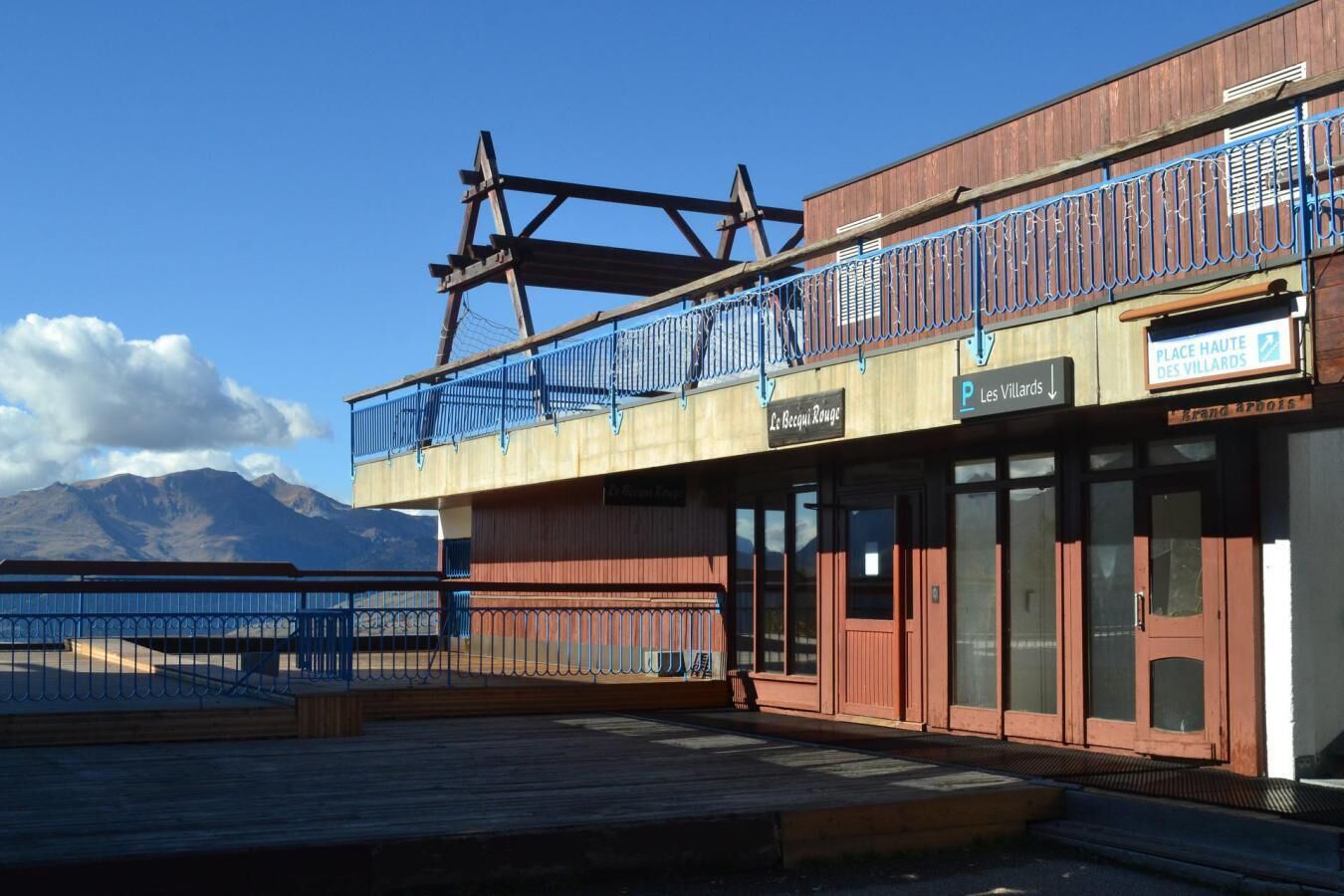 Ein Gebäude mit einer Holzfassade, einem Balkon mit blauen Geländern und einem Schild mit der Aufschrift 'Place Haute des Villards'.
