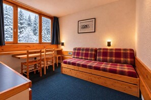 A cozy cabin interior with a wooden bench, a plaid sofa, and a dining table.