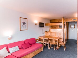 Une pièce chaleureuse avec un canapé rouge, une table à manger en bois et des chaises.