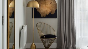 A modern room with a large mirror, a floor lamp, a chair, a painting, and a window with curtains. - Fitzrovia apartments by DMONTRIO (London)