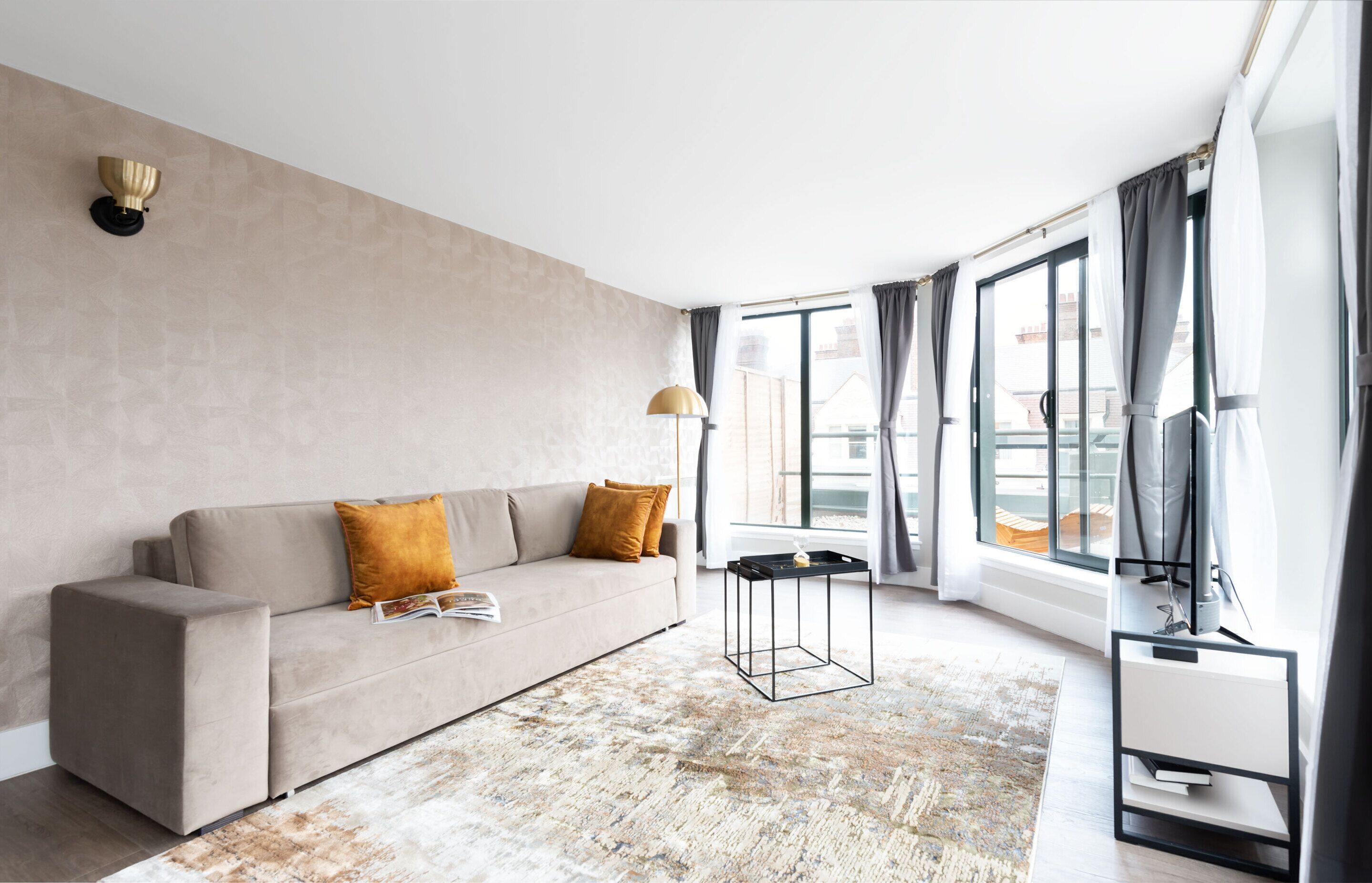 Une chambre d’hôtel moderne dotée d’une grande fenêtre, d’un canapé, d’une table basse et d’un meuble pour la télévision.
