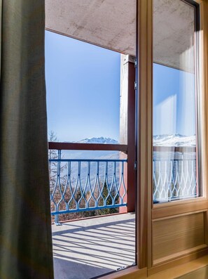 A balcony with a metal railing, a clear view of snow-capped mountains, and a concrete floor.