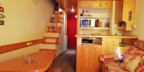 A compact kitchen with wooden cabinets, a microwave, and a small dining area with a table and chairs.