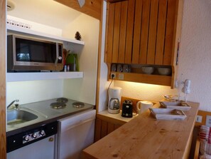 A compact kitchen with a microwave, stove, sink, and a coffee maker.