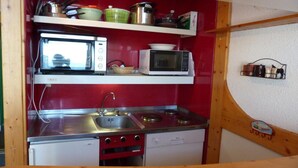 Una cocina compacta equipada con microondas, tostadora y estufa.