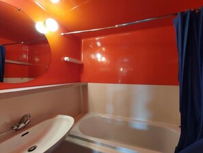 Ein Badezimmer mit weißem Waschbecken, einer Badewanne und einem Spiegel.