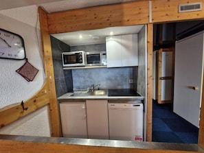 A compact kitchen with a microwave, sink, and two dishwashers.