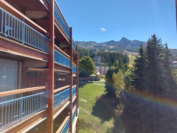 A multi-story building with balconies overlooking a mountainous landscape.