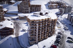 Korkea hotellirakennus, jossa on useita parvekkeita, ja sen ympärillä on lumipeitteisiä teitä ja muita rakennuksia.