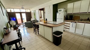 Une cuisine compacte dotée d’un îlot central, d’un coin repas avec des chaises et d’une poubelle.