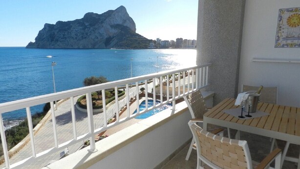 Ein Balkon mit Meer- und Bergblick, ein Tisch mit Stühlen sowie ein kleiner Poolbereich.