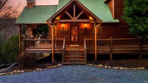 A rustic lodge with a stone chimney, wooden porch, and a sign indicating a retreat. - Pet Friendly Cabin|Hot Tub|Pool Table|Outdoor Fireplace (Blue Ridge)