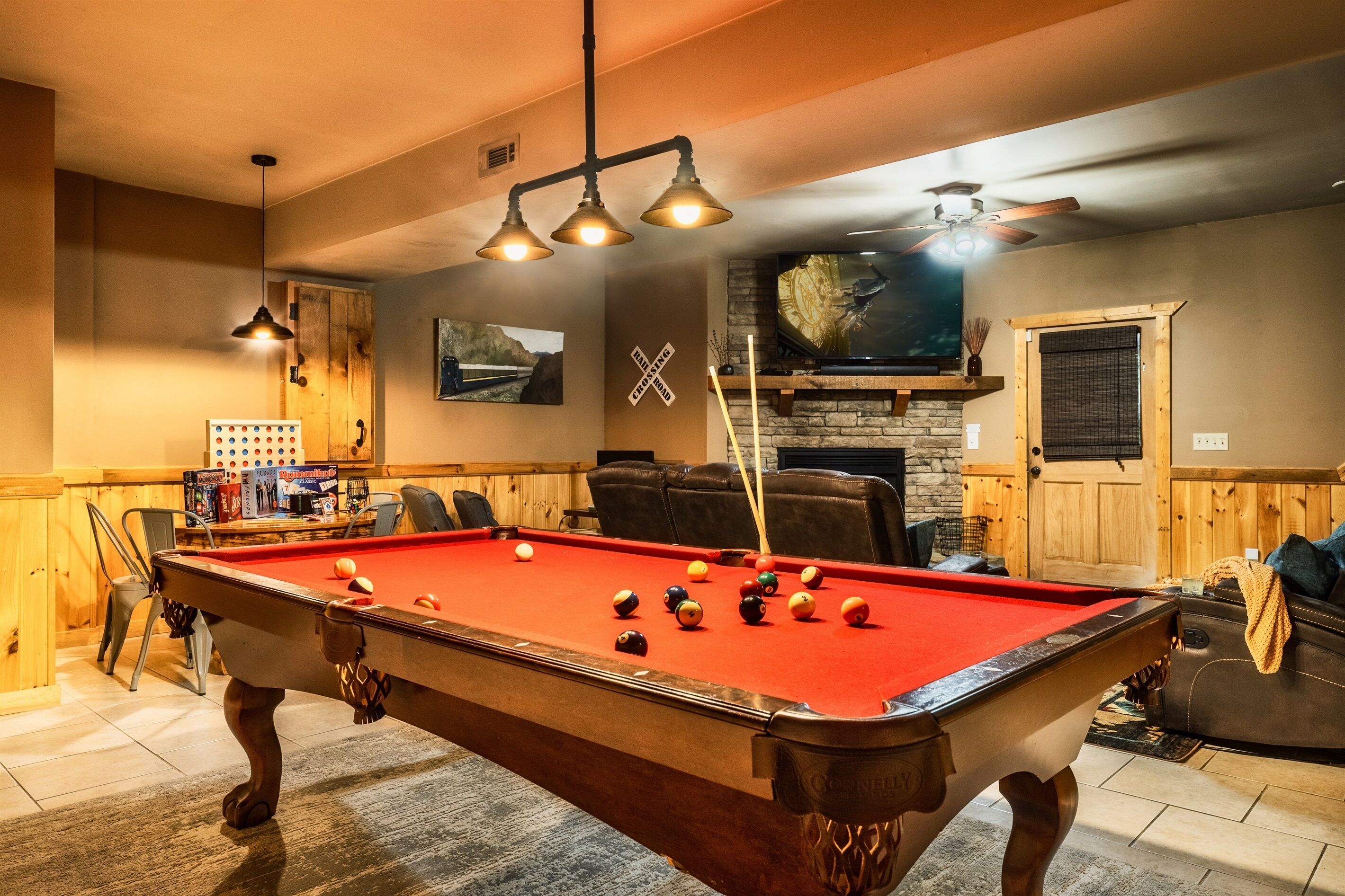 A pool table with balls, a wooden chair, a fireplace, and a television.
