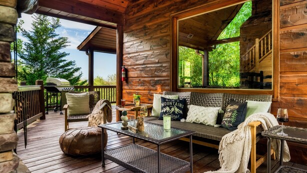 A wooden cabin with a porch, furnished with a sofa, chairs, and a table. - Pet Friendly Cabin|Hot Tub|Pool Table|Outdoor Fireplace (Blue Ridge)