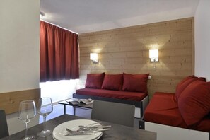 Relax in a cozy room with a comfortable sofa and dining area, featuring a wooden headboard and wall-mounted lights.