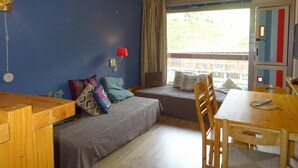 Una habitación con una cama, una mesa de madera y un ventanal con cortinas.