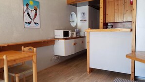 Una cocina compacta con microondas, cafetera y armarios de madera.