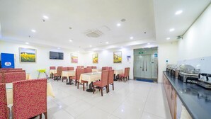Ein Essbereich mit Tischen, Stühlen, einer Buffettheke und einem Fernseher an der Wand.