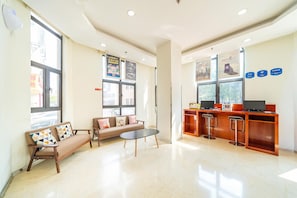 A modern waiting area with a sofa, a coffee table, and a reception desk with a computer and a phone. - Hanting Hotel (Shanghai)