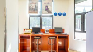 Ein Empfangsschalter mit zwei Computern, einem QR-Code-Automaten und einem Fenster mit Blick auf Bäume.