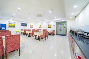 A dining area with tables and chairs, a buffet counter, and a television on the wall. - Hanting Hotel (Shanghai)