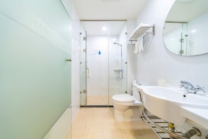 A modern bathroom with a glass shower enclosure, a white toilet, and a sink with a mirror above it. - Hanting Hotel (Shanghai)