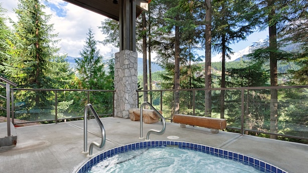 A hot tub with a stone pillar, metal railings, and a bench. - Greyhawk by Whistler Premier (Whistler)