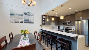 A modern kitchen with dark cabinets, stainless steel appliances, and a bar area. - Greyhawk by Whistler Premier (Whistler)