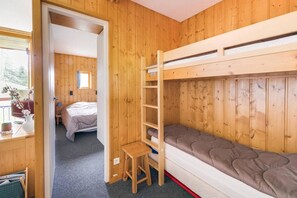 Una stanza in legno con letti a castello, un piccolo tavolo e un letto con testiera.