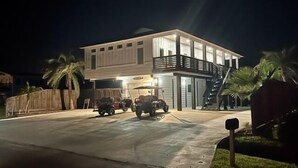 A two-story building with a balcony and a garage. - Heated Private Pool, Yard Games, Golf Cart Included (Port Aransas)