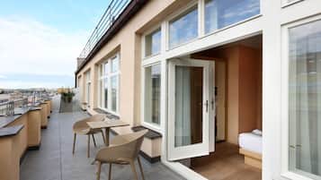 Un balcon avec une table et des chaises, un lit et une vue sur la ville.