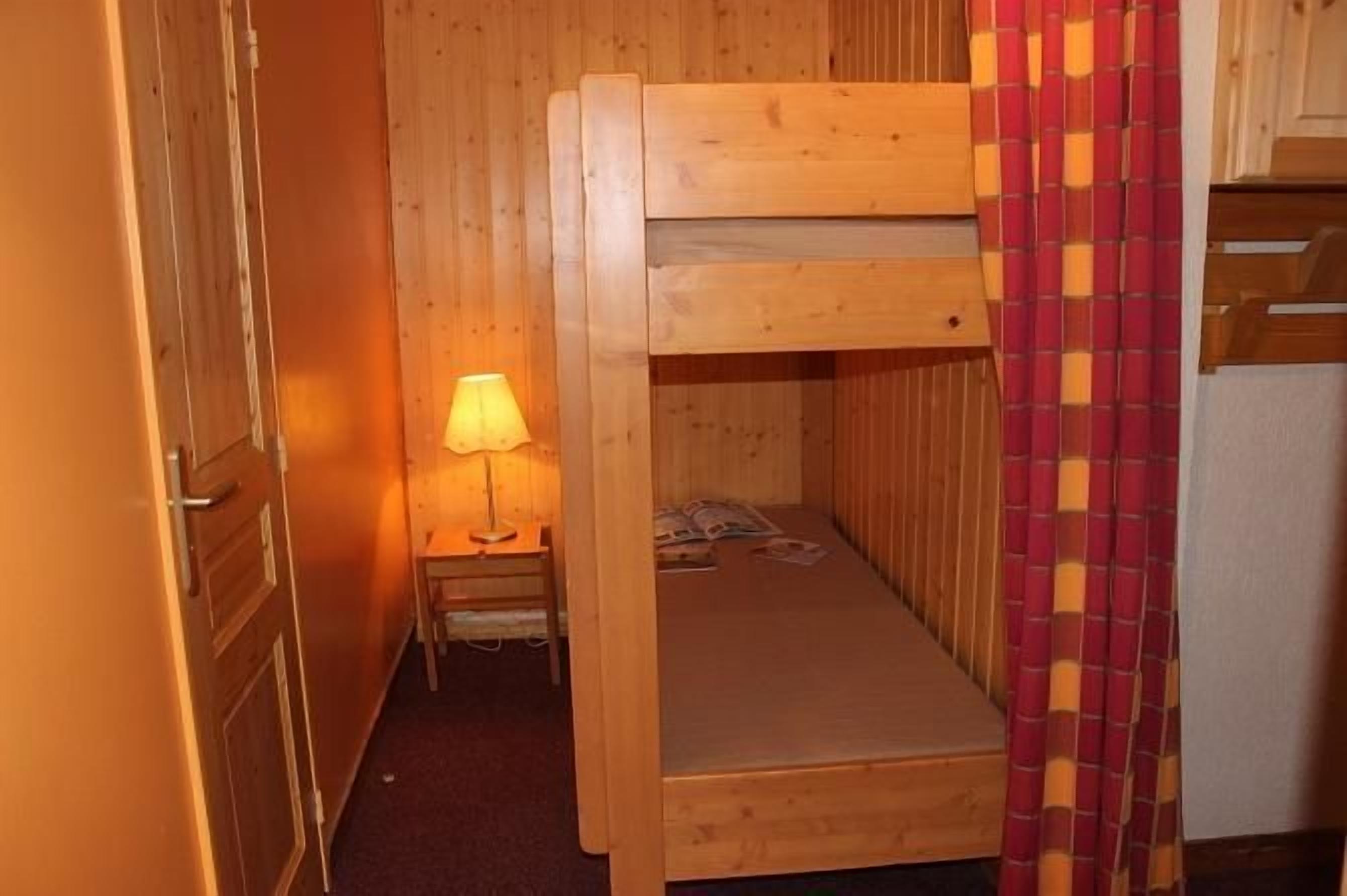 A bunk bed room with a nightstand and lamp.