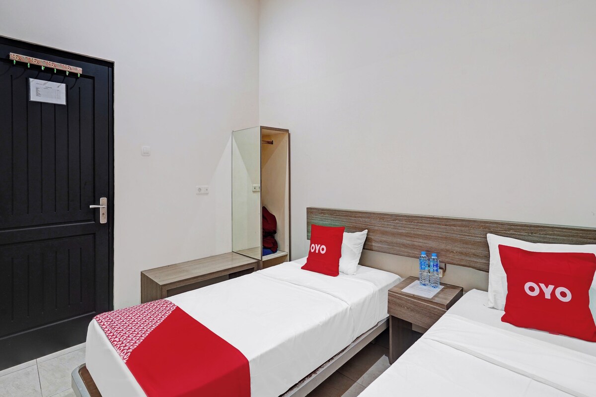 A hotel room with a bed, a nightstand, a mirror, and a wardrobe.