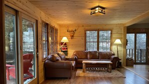 A cozy cabin interior with a wooden floor, leather sofas, and large windows. - Storybook Cabin - Private Stream, Incredible Canyon View, Starlink Internet (Bellvue)