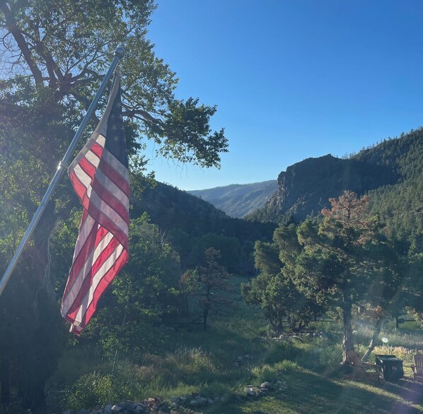 Experience the serene beauty of nature with a flag waving gently in the breeze, set against a backdrop of lush hills and a clear sky.