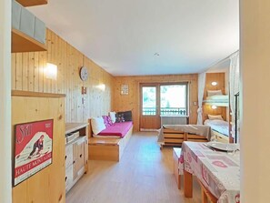 Viehättävä vuoristomökki, jossa on puinen sisustus, ruokailutila, keittiö ja parveke, jolta on kaunis näköala.