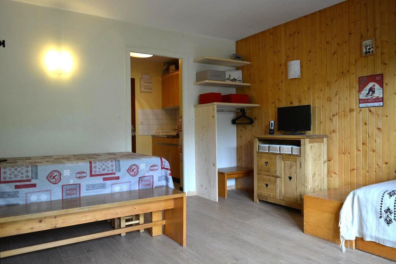 Une pièce comprenant un lit, une armoire en bois, un téléviseur et une petite table.