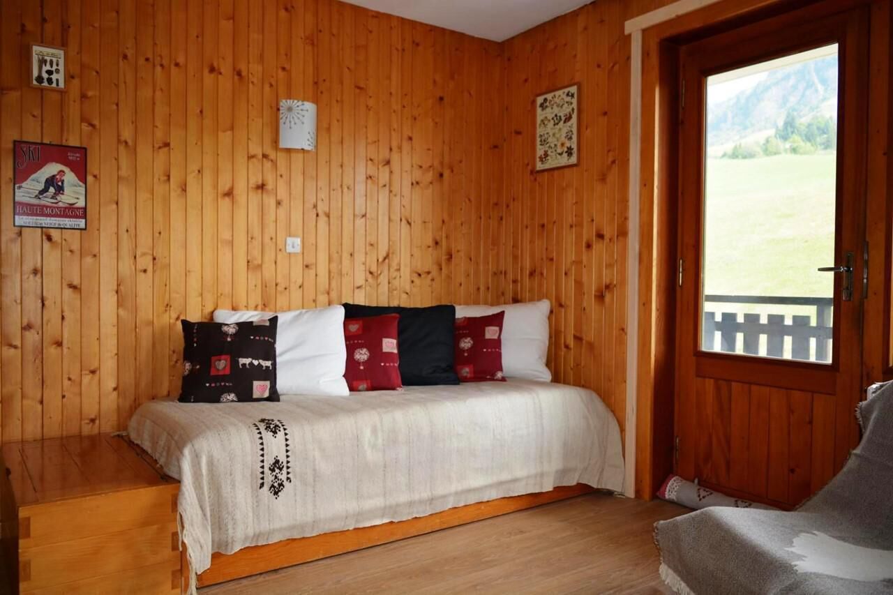 Ein Zimmer aus Holz mit einem Bett, einer Holztür und einem Poster an der Wand.