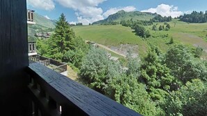Uma varanda com vista para uma paisagem verde, incluindo árvores e uma colina distante.