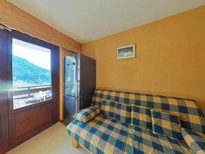 A room with a checkered sofa, a refrigerator, and a window with a view of a mountainous landscape. - Ground floor, tv, 21m², Le Grand Bornand (Le Grand-Bornand)