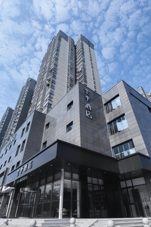 A modern hotel building with a prominent sign, large windows, and a clear view of the sky.