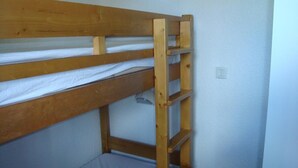 Una cama litera con estructura de madera y ropa de cama blanca.