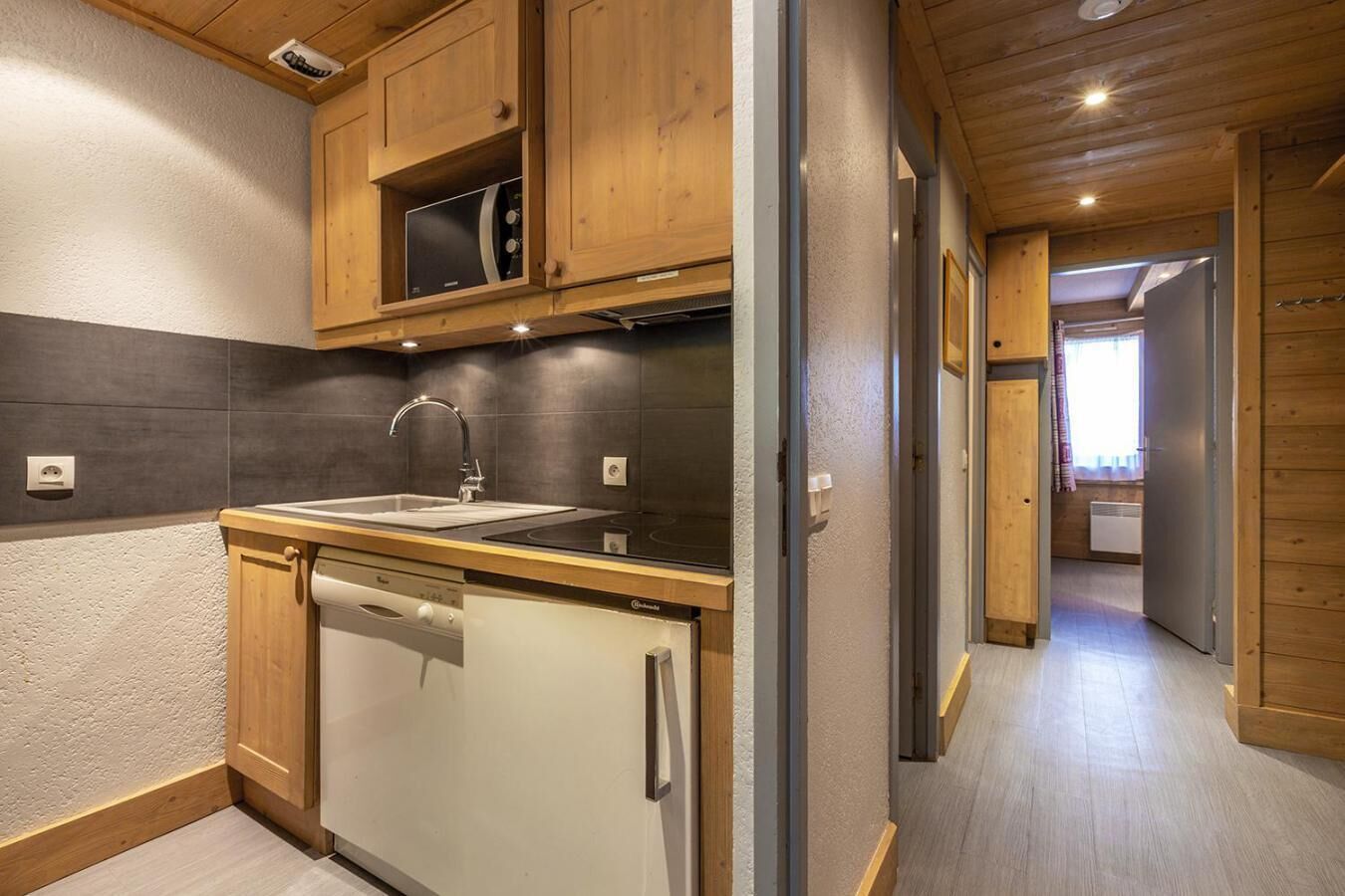 Una cocina moderna con gabinetes de madera, lavavajillas integrado y pileta de acero inoxidable.