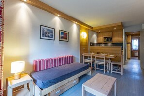 A compact living space with a bed, a small table, a bench, a kitchenette, and a dining area. - 150m from shops, 4th floor, view ski slopes, balcony, ski locker, 36m², Méribel-Mottaret (Méribel - Les Allues)