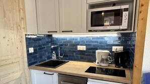 A compact kitchen with a microwave, coffee maker, and dishwasher. - 20m from ski slopes, 1st floor, view ski slopes, balcony, tv, 26m², Méribel-Mottaret (Méribel - Les Allues)