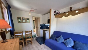 A compact living space with a dining area, a blue sofa, and a kitchenette. - 20m from ski slopes, 1st floor, view ski slopes, balcony, tv, 26m², Méribel-Mottaret (Méribel - Les Allues)