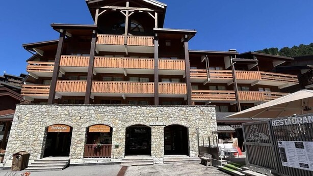 A multi-story building with a stone facade, multiple balconies, and a restaurant sign. - 20m from ski slopes, 1st floor, view ski slopes, balcony, tv, 26m², Méribel-Mottaret (Méribel - Les Allues)