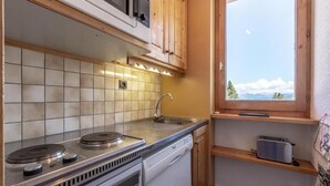 A compact kitchen with a stove, sink, and wooden cabinets.