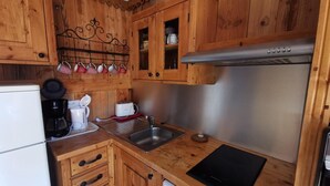 Cozinha compacta com armários de madeira, pia de aço inoxidável, cafeteira e lava-louças.