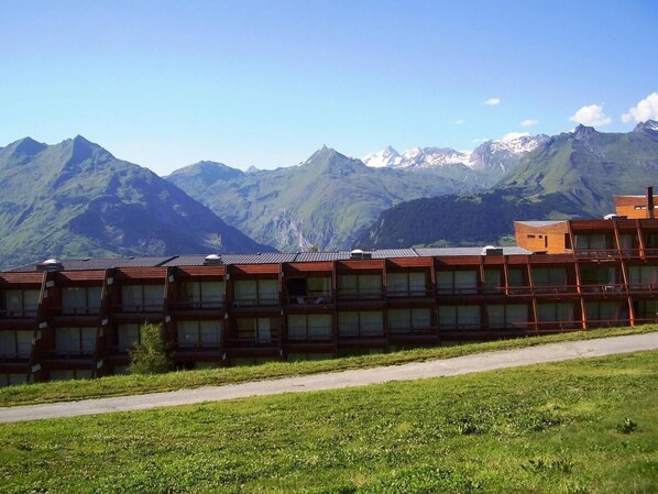 A row of wooden cabins with large windows, set against a backdrop of mountains.